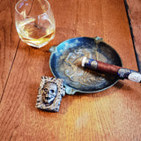 lighter zippo mummy in bronze posed on a table with a cigar an ashtray and a glass of whiskey